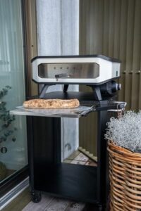 Elevate your outdoor dining experience with cozze's innovative table featuring a extendable chopping board, perfect for pizza ovens up to 60cm. Includes stainless steel hooks and space for gas bottle storage.
