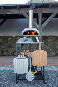 Discover the Ooni Medium Modular Table - a stainless steel pizza oven stand with grill & barbecue capabilities. Perfect for outdoor cooking, this cart features a compact 31x22x35 inch design.