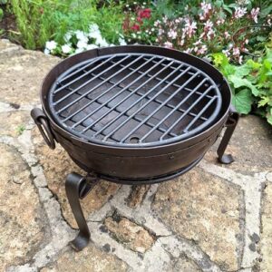 Savor the warmth of outdoor gatherings with this genuine handmade steel fire pit, complete with stand and grill. Perfect for BBQs and camping trips.